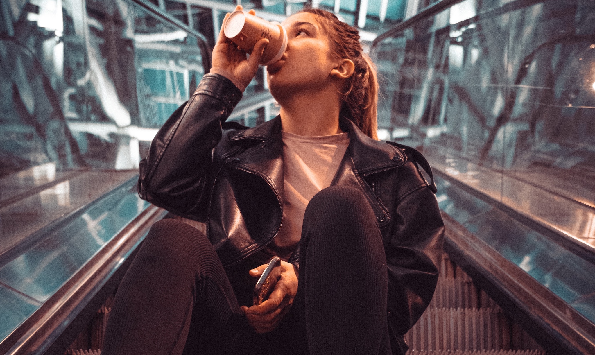 young woman drinking coffee in an airport, which is bad for jet lag